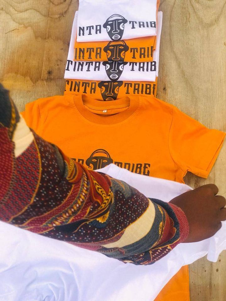 A person is holding a t-shirt that says tinta tribe