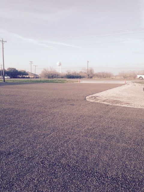A car is parked in a parking lot with a water tower in the background.