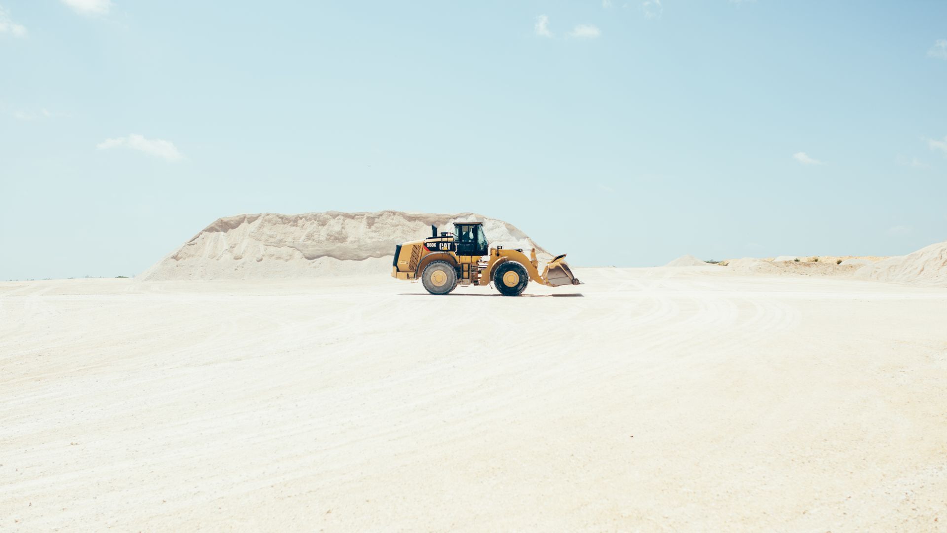 A bulldozer is driving through a desert.