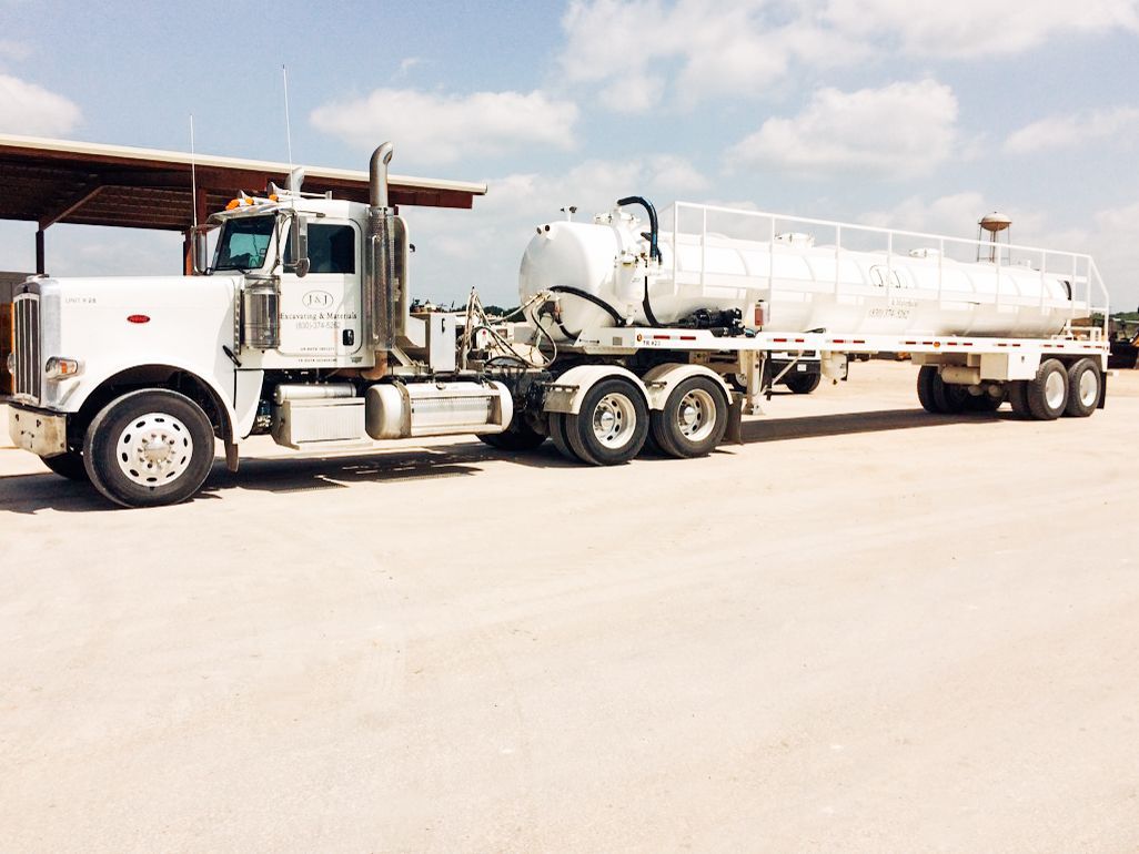 A white semi truck with a tanker trailer attached to it