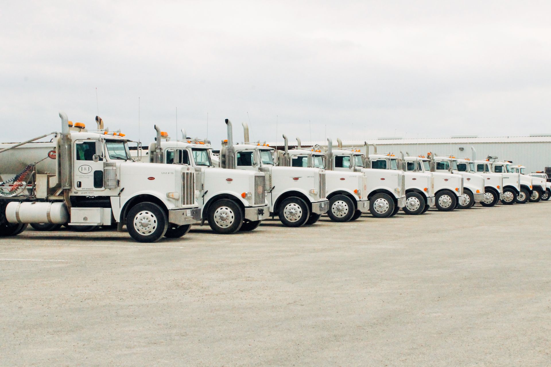 A row of semi trucks are parked in a parking lot.