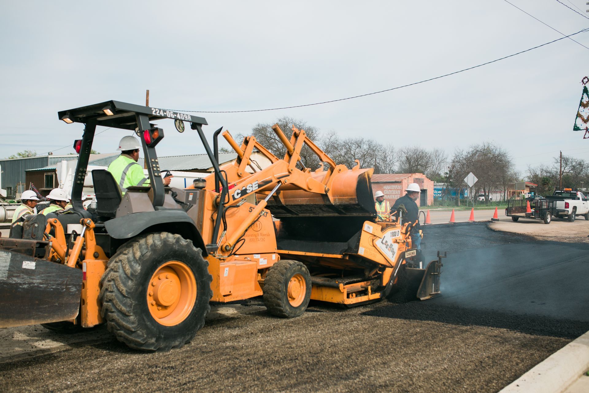 A tractor is being used to spread asphalt on a road.