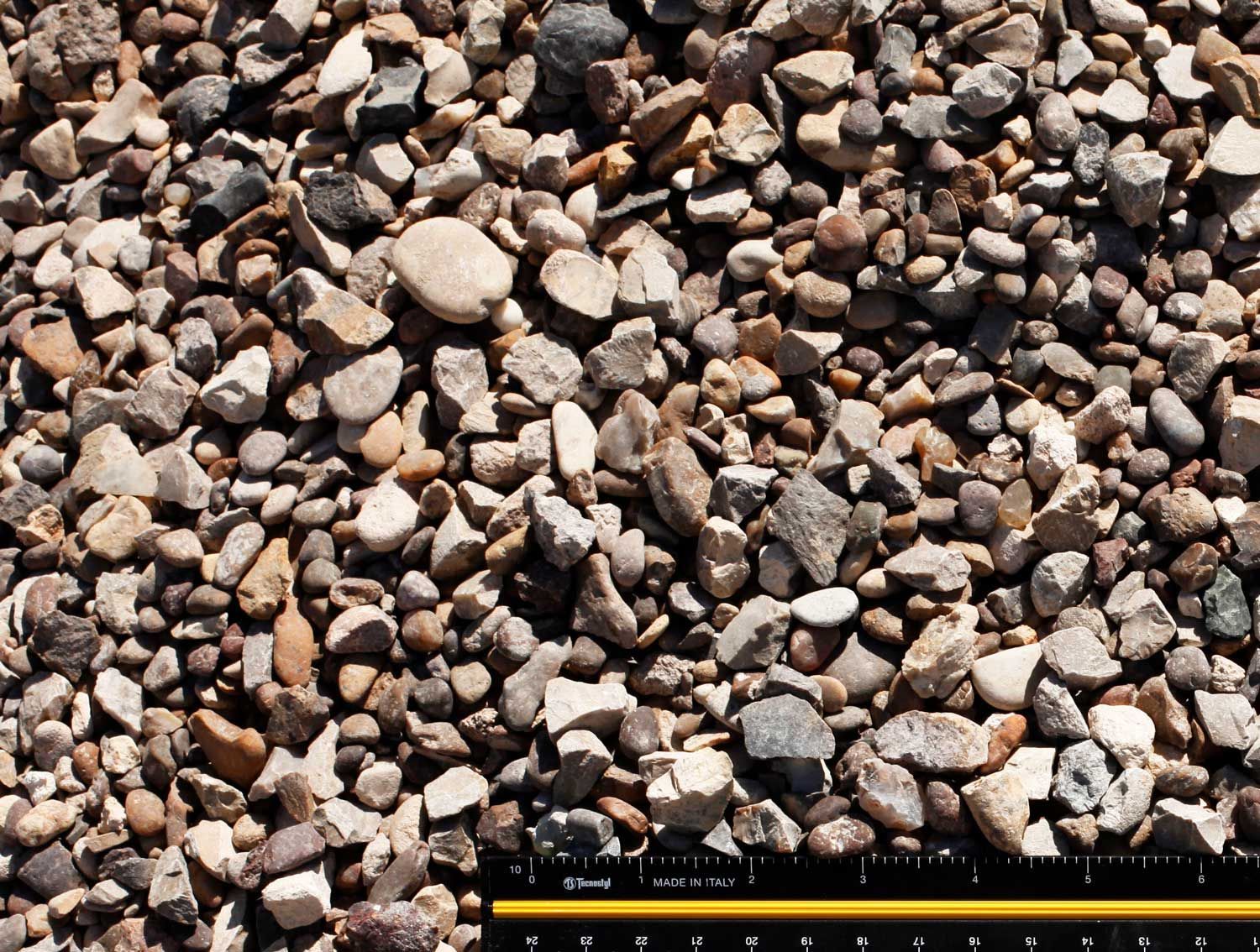 A pile of rocks is being measured by a ruler.