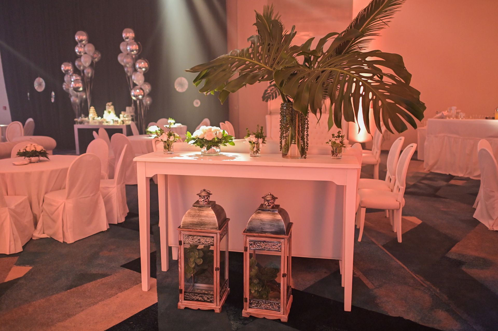 Una mesa con flores y linternas en una habitación con mesas y sillas.