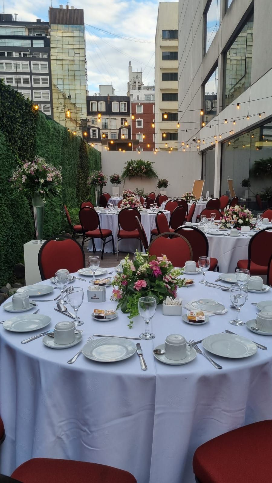 Una mesa preparada para una fiesta con platos, tazas, utensilios y flores sobre ella.