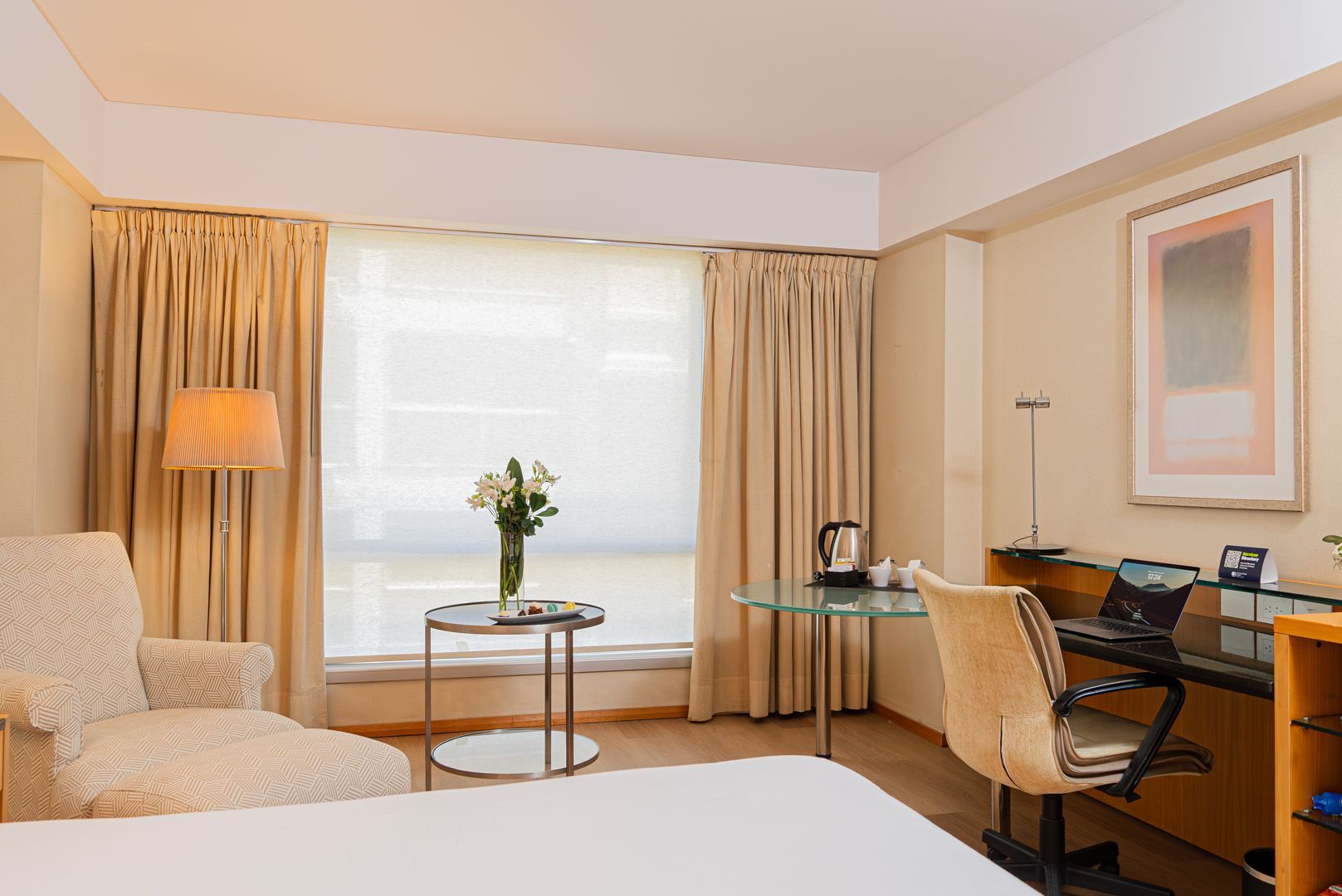 Una habitación de hotel con cama, silla, escritorio y ventana.