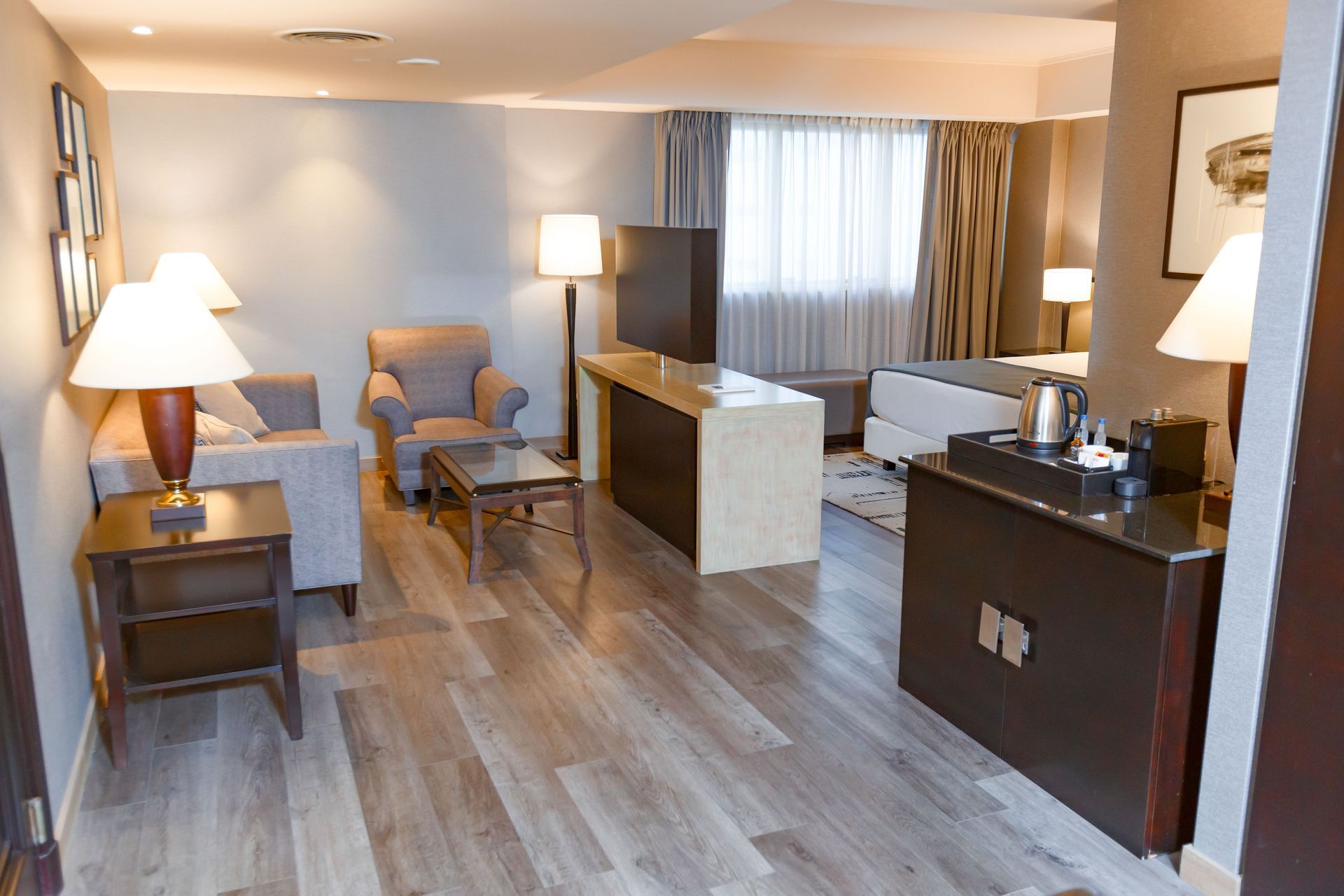 Una habitación de hotel con sofá, silla, mesa y lámparas.