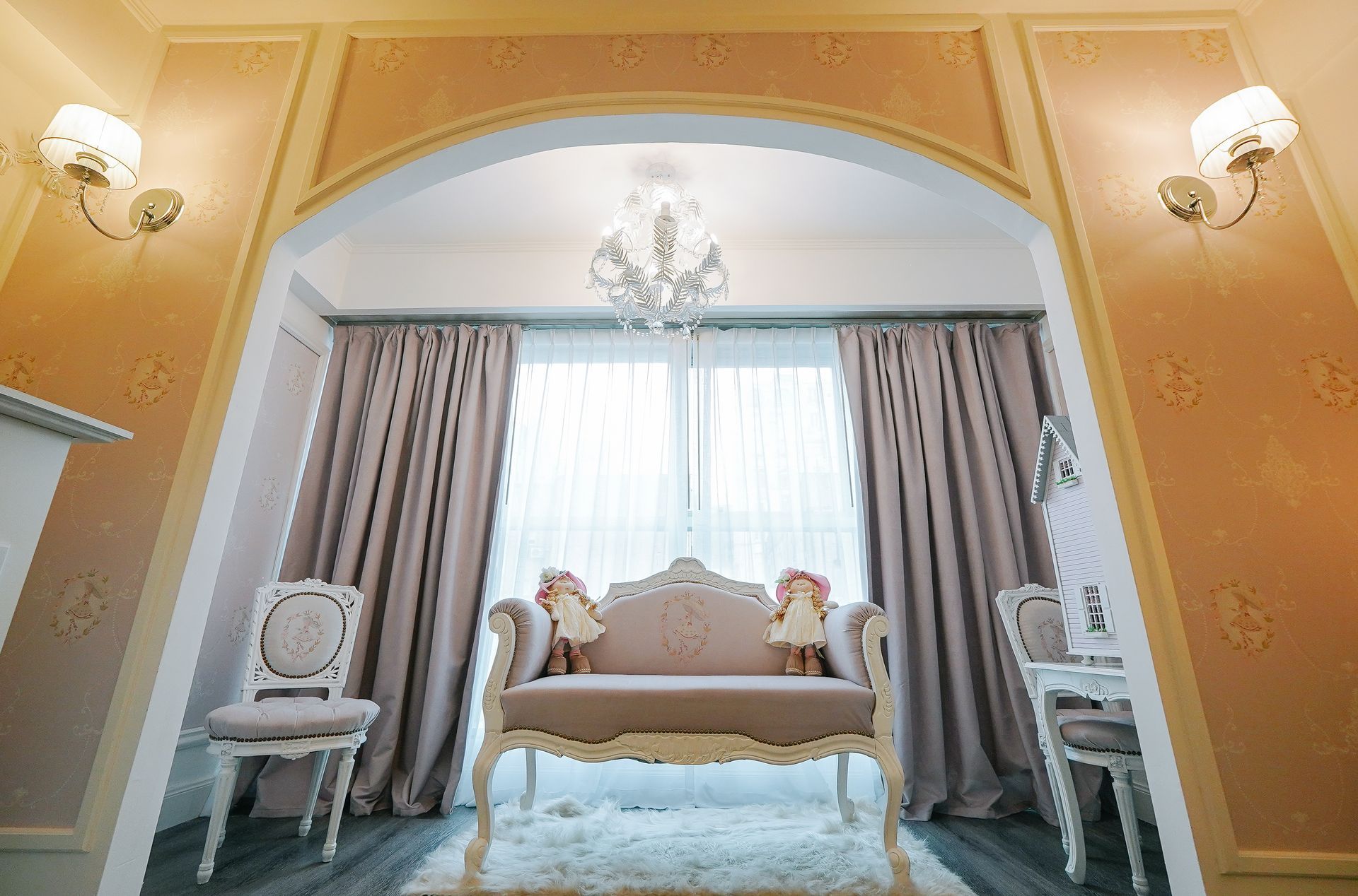 Una sala de estar con un sofá, sillas, cortinas y una lámpara de araña.