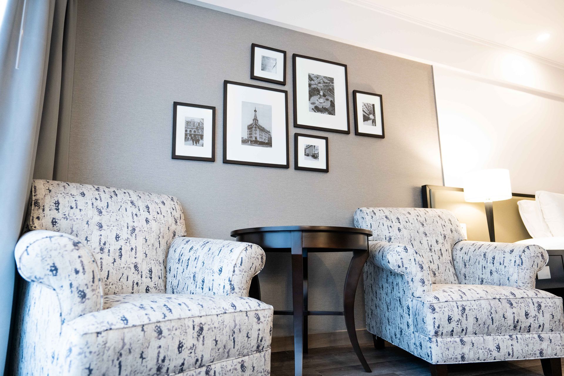 Dos sillas y una mesa en una habitación de hotel con cuadros en la pared.