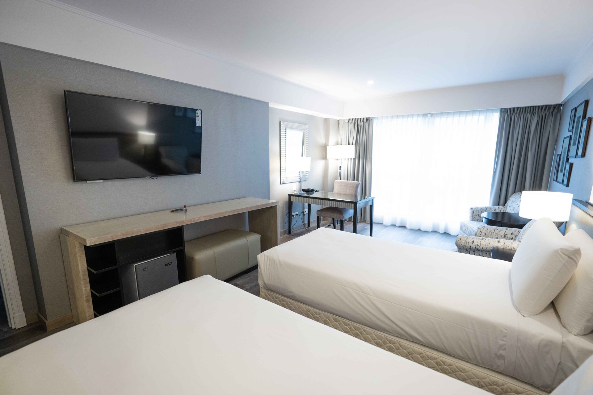 Una habitación de hotel con dos camas y un televisor de pantalla plana.