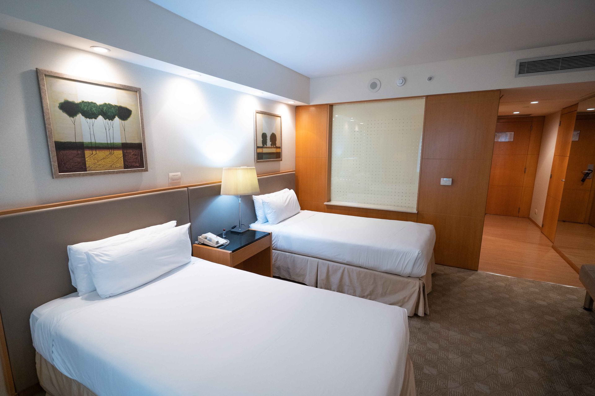 Una habitación de hotel con dos camas y una lámpara.