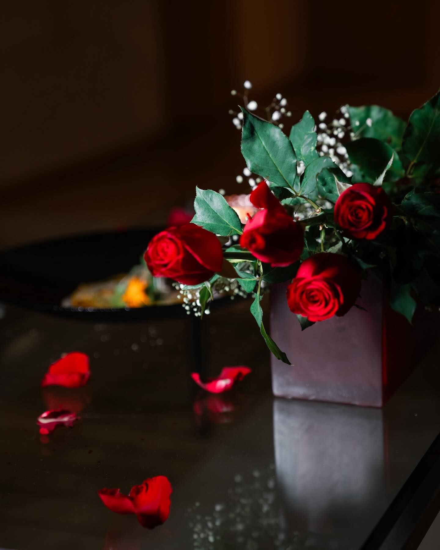 Un jarrón lleno de rosas rojas reposa sobre una mesa.