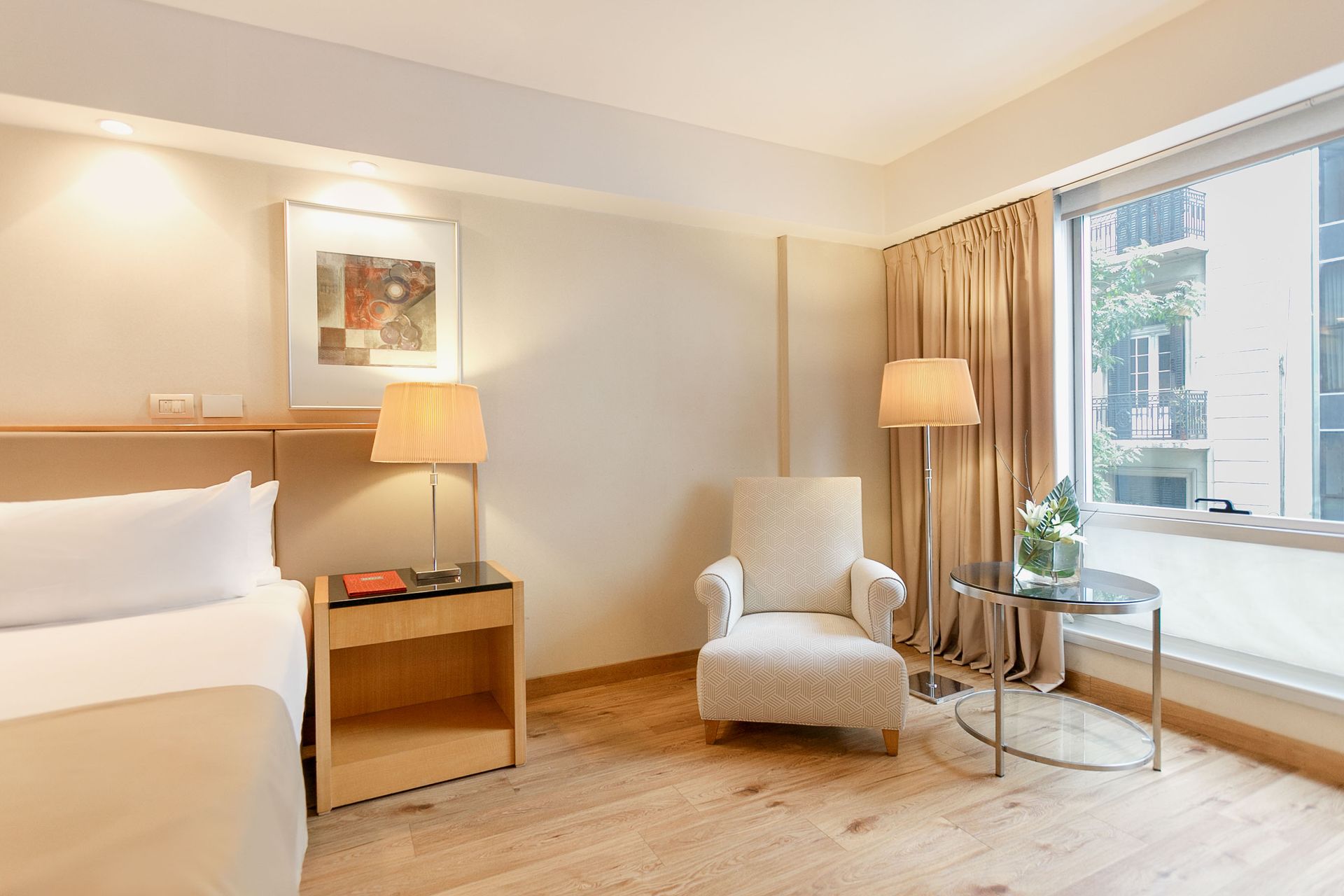 Una habitación de hotel con una cama, una silla, una mesa y una ventana.