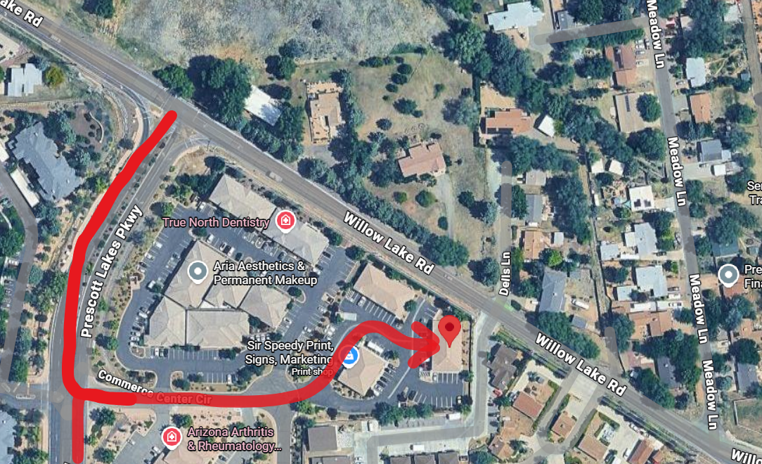 Aerial view of a commercial area, with red path indicating a route to a building. Buildings and streets are visible.