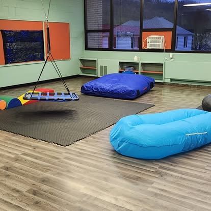 A room with a lot of toys on the floor and a swing.