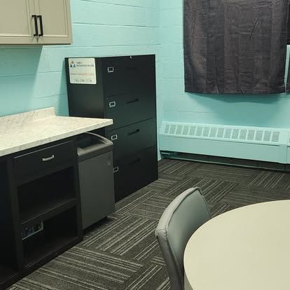 A room with a table and chairs and a filing cabinet.