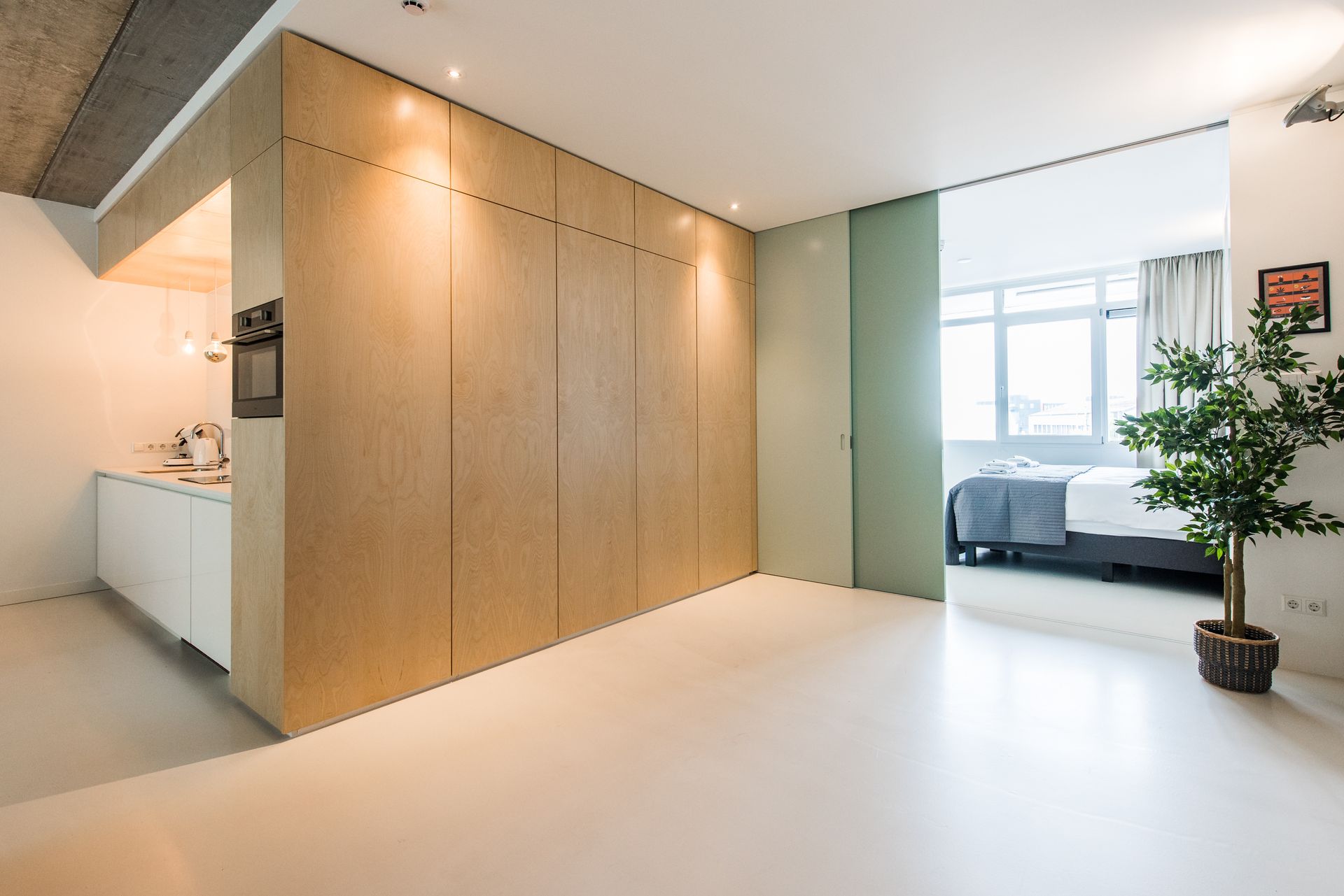 Modern appartementinterieur met een houten wand, keuken en slaapkamer zichtbaar.