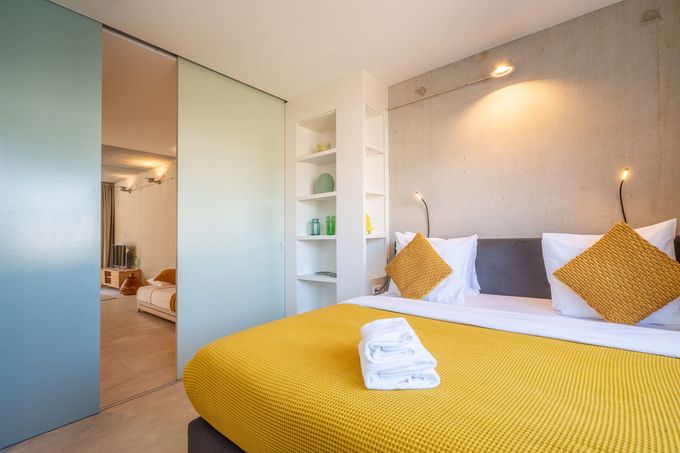 Eethoek met witte tafel, verschillende stoelen, hanglampen en een potplant.
