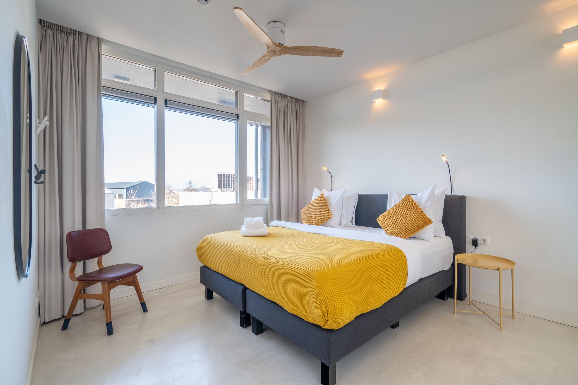 Moderne woonkamer in een appartement met een bruine bank, een witte eettafel en lichte houten kasten.