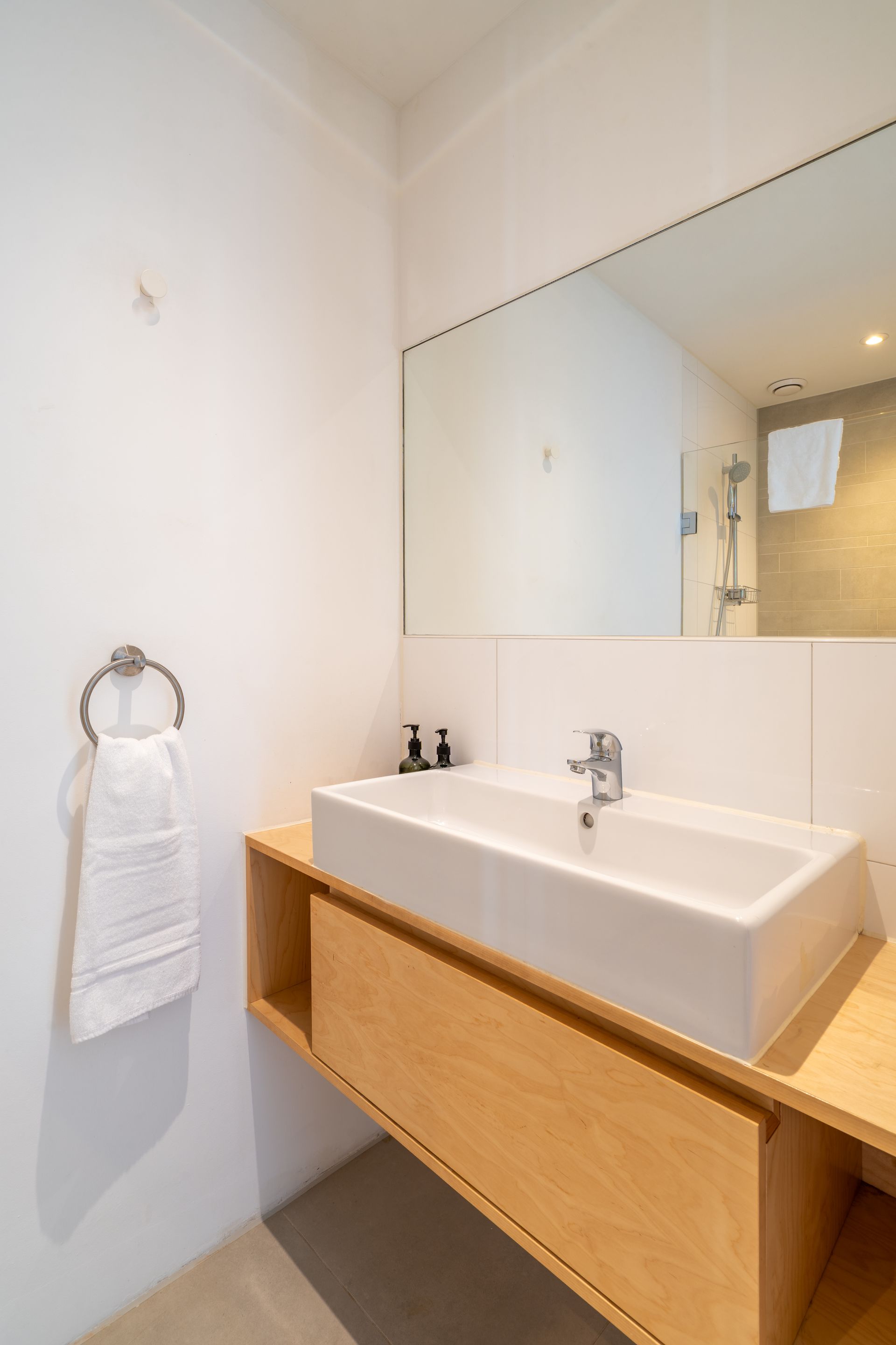 Een moderne badkamerkast met  rechthoekige wastafel, een kastje en een grote spiegel 