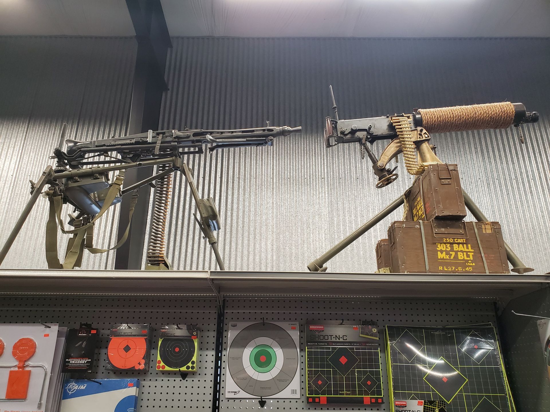 Interior view of a gun store with rifles displayed on racks. Various merchandise on shelves. Door visible.