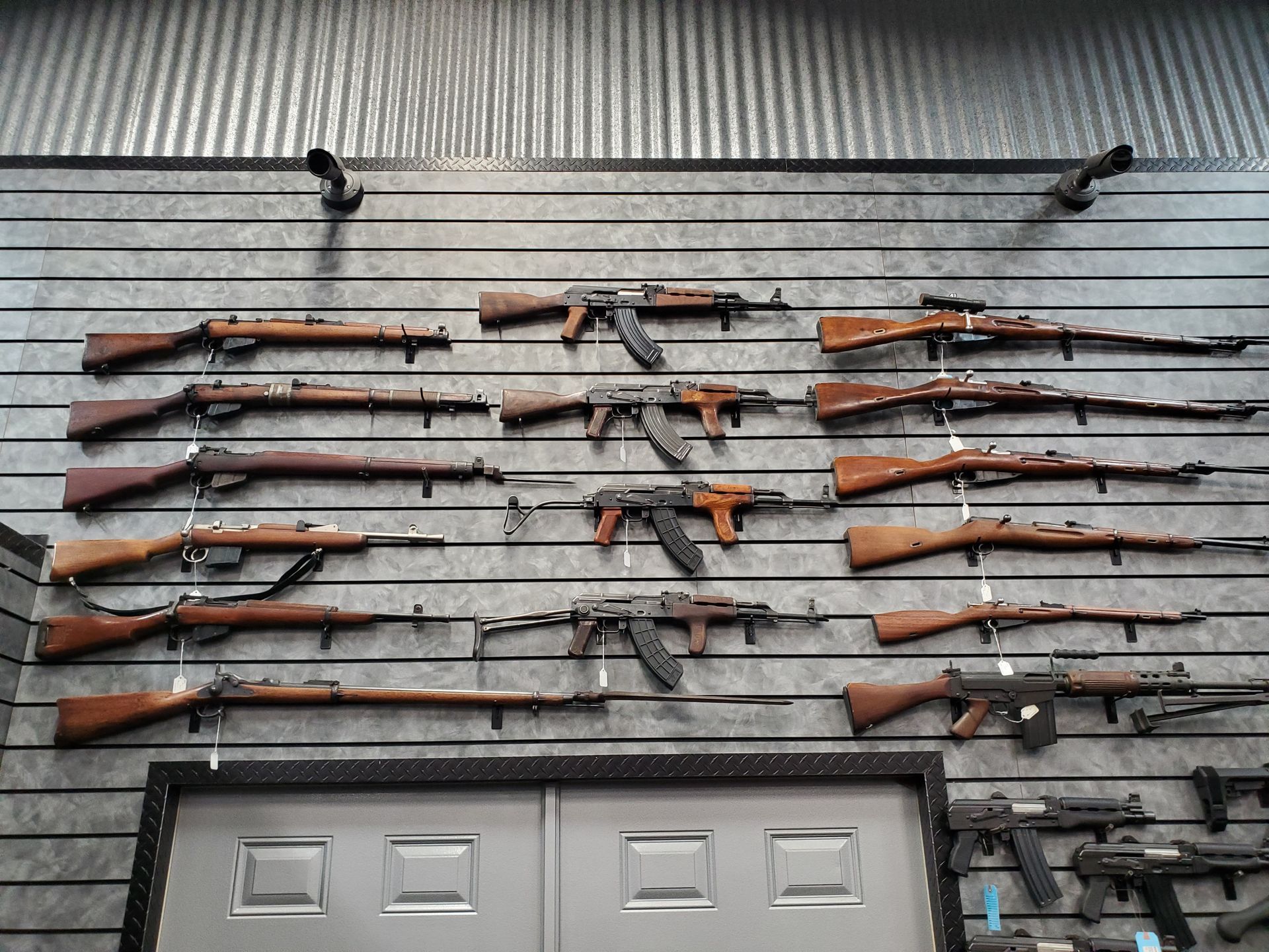 Hunter Firearms building with vehicles and a wooden fence. Blue sky, green grass.