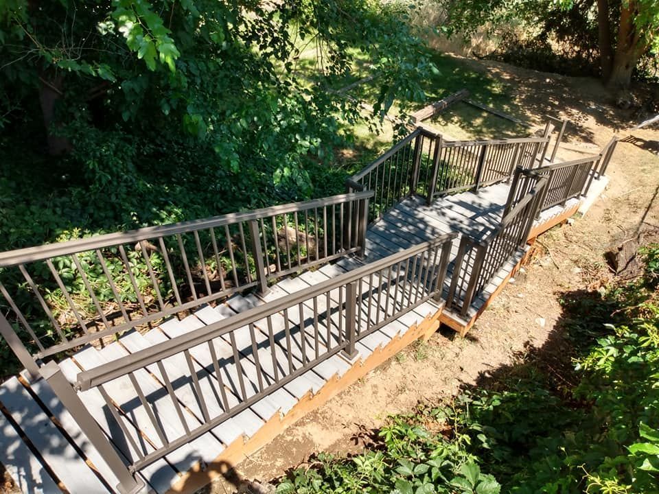 Wooden staircase with metal railings descending into a wooded area.