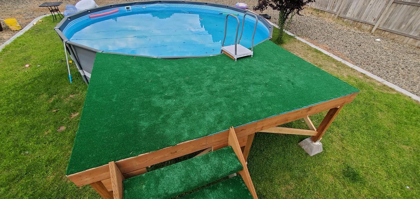 Above-ground pool with a wooden deck covered in green turf. The deck has a small ladder.