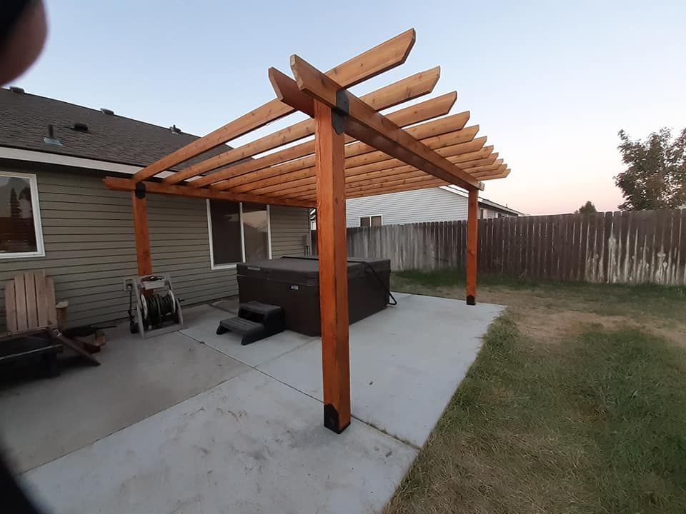 Wooden pergola over a hot tub on a concrete patio.