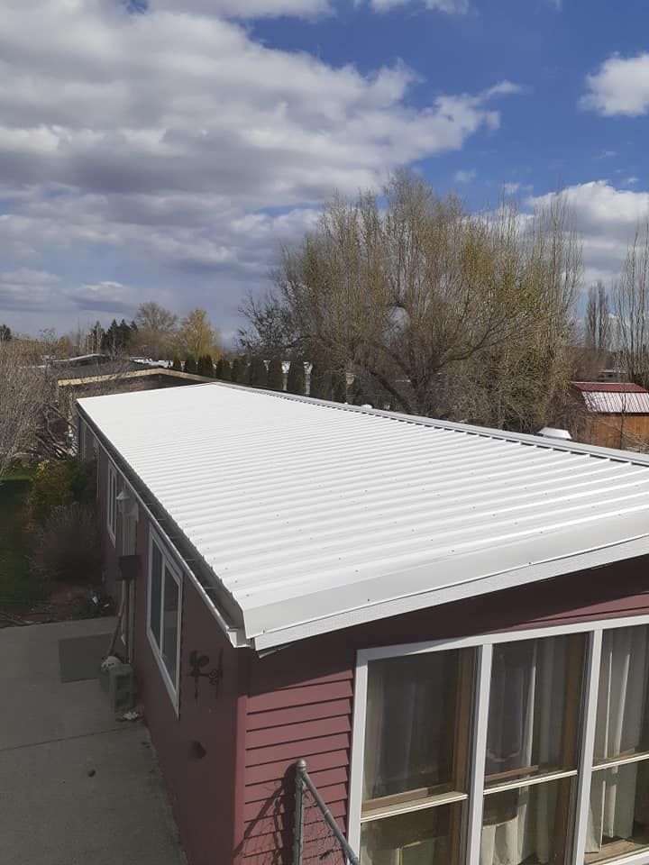 White metal roof on a red building under a partly cloudy blue sky.