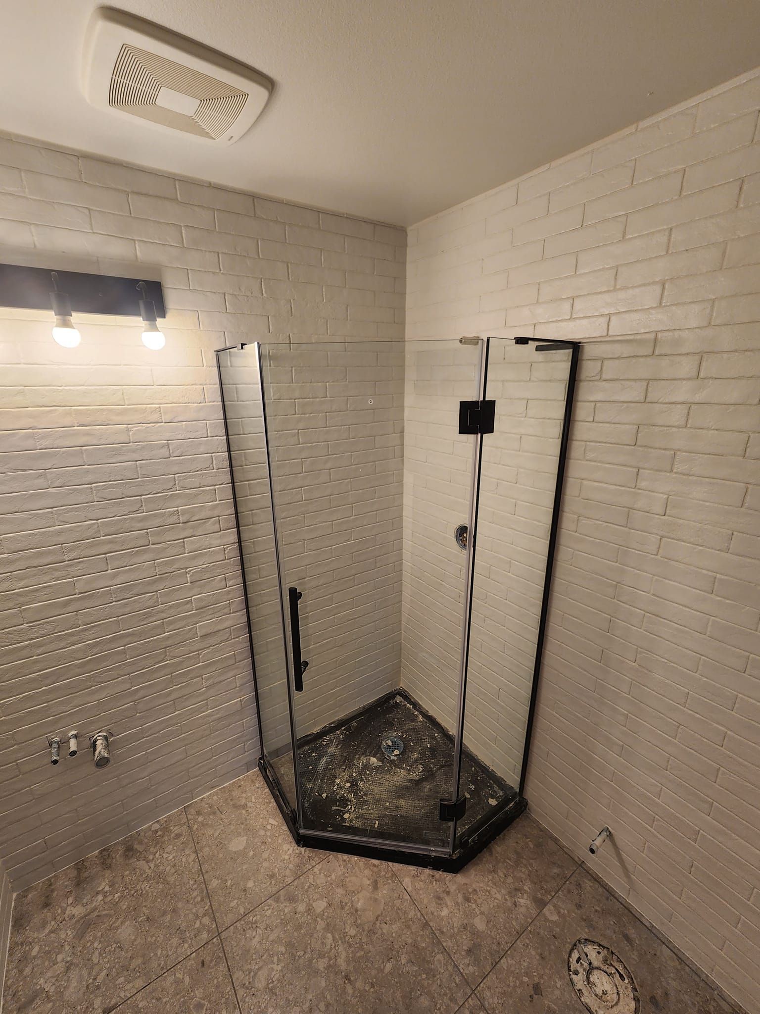 Bathroom with a glass shower enclosure and light-colored tile walls.