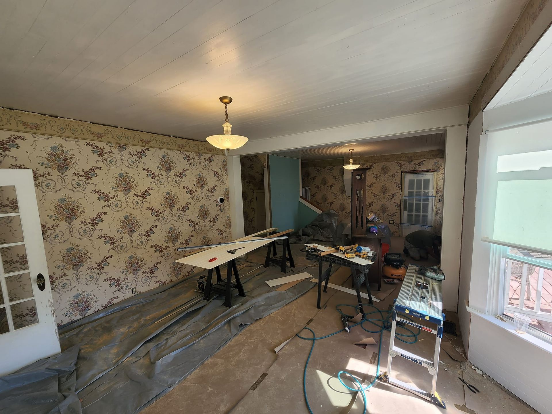 Room under renovation with wallpaper, worktables, and tools.
