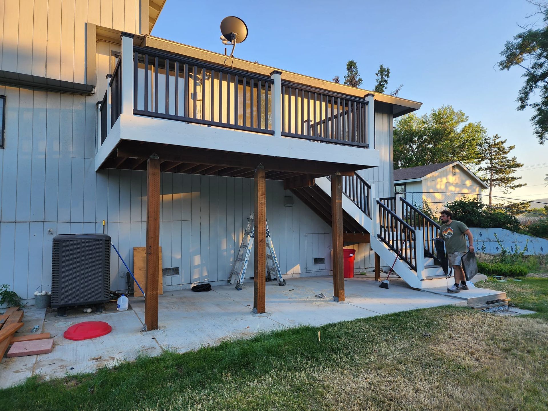 Deck attached to a two-story house. A person walks on the stairs with a bag. The deck and stairs 