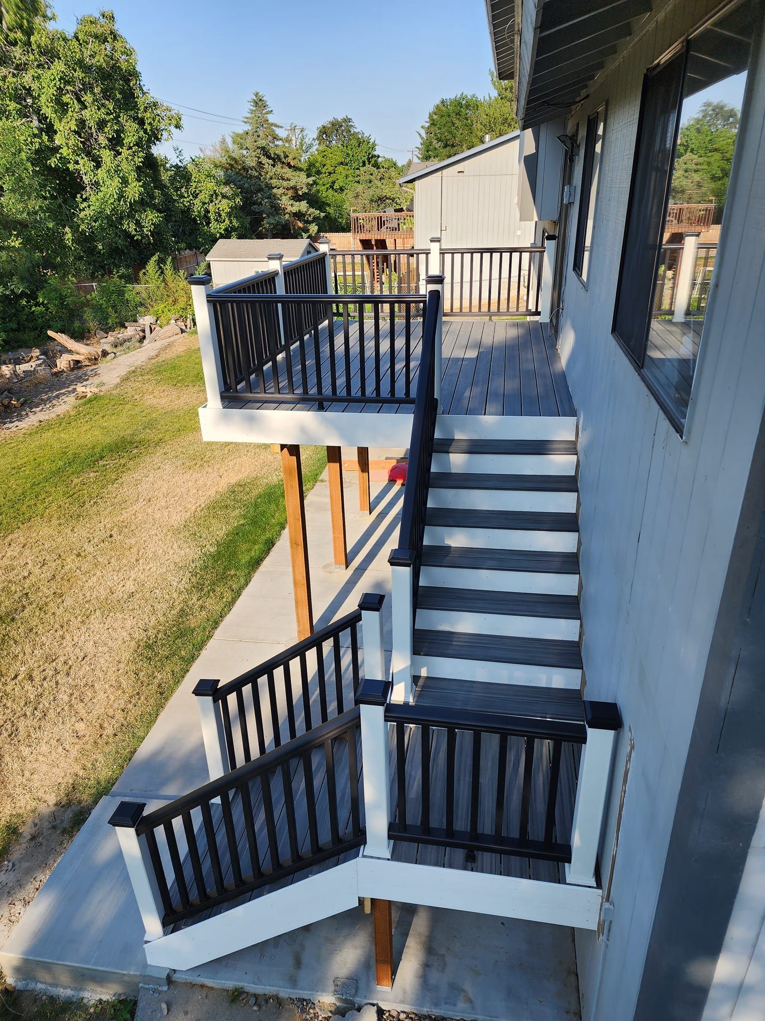 Deck with black railings, white posts, and gray steps descends from a building.
