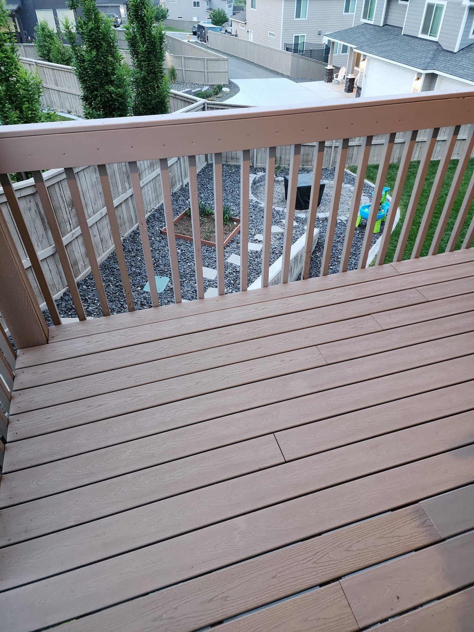 Wooden deck overlooking a backyard with a rock garden and grass, viewed from above.