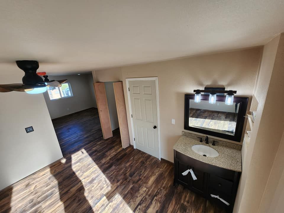 Bathroom with dark wood floors, dark vanity with a granite countertop, and a ceiling fan.