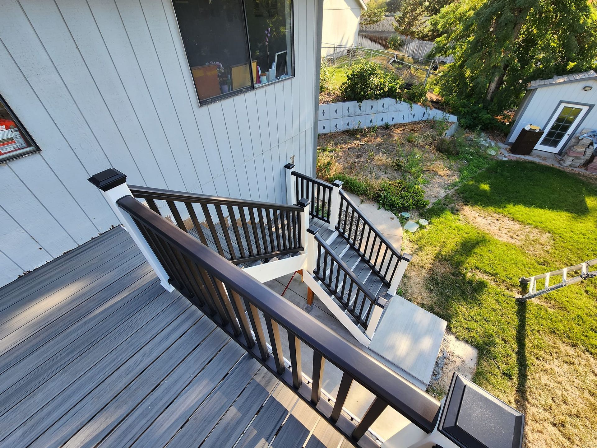 Deck with dark railing and stairs leading down to a grassy yard.