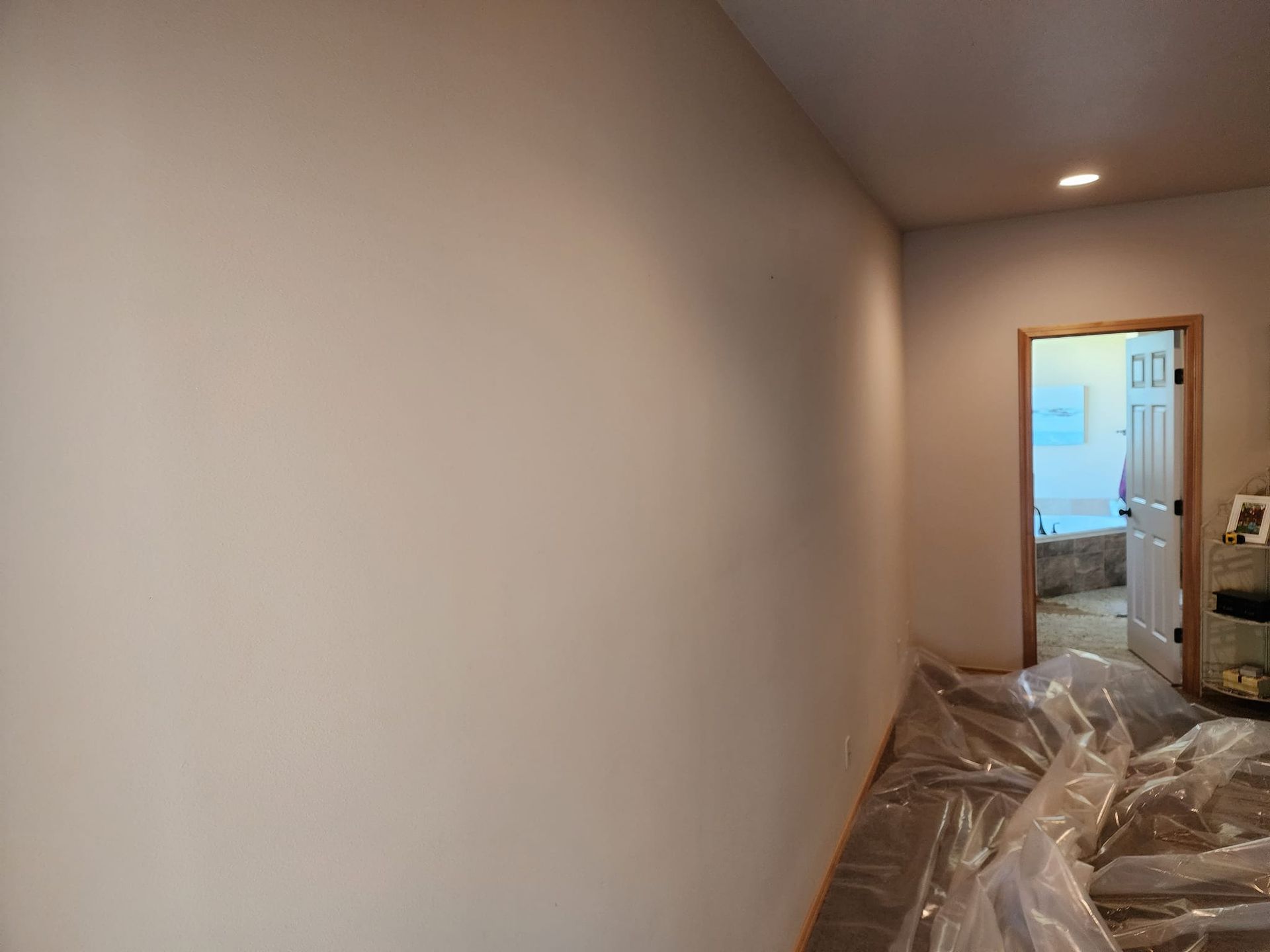 Interior wall painted beige with an open doorway leading to another room. Protective plastic covers the floor.