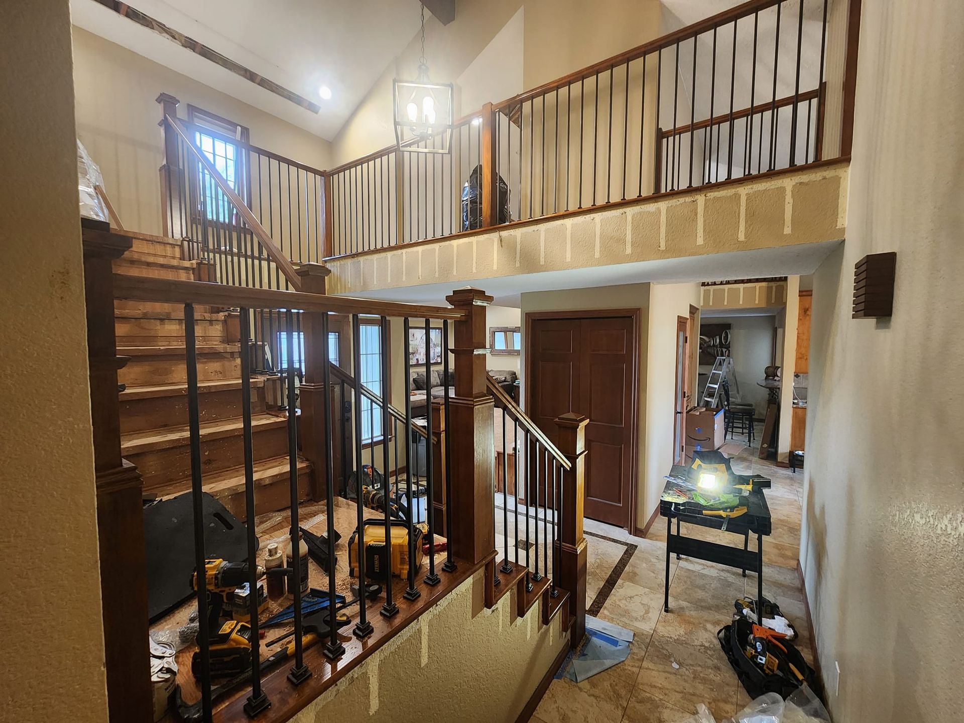 Interior shot of a stairwell under construction. Wooden banisters with black metal spindles and tools visible on the floor.