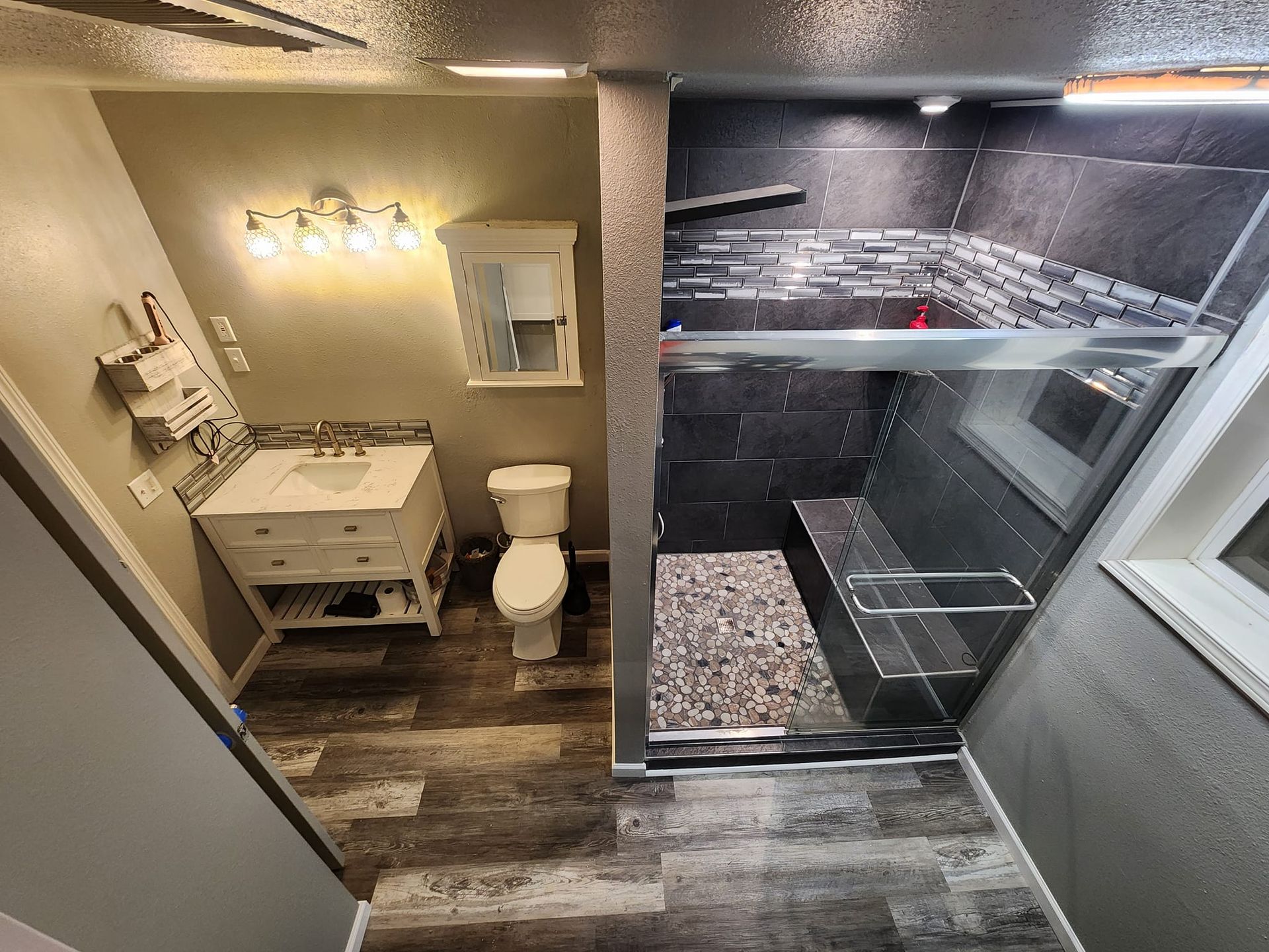 Bathroom with a vanity, toilet, and a walk-in shower with a mosaic tile floor.