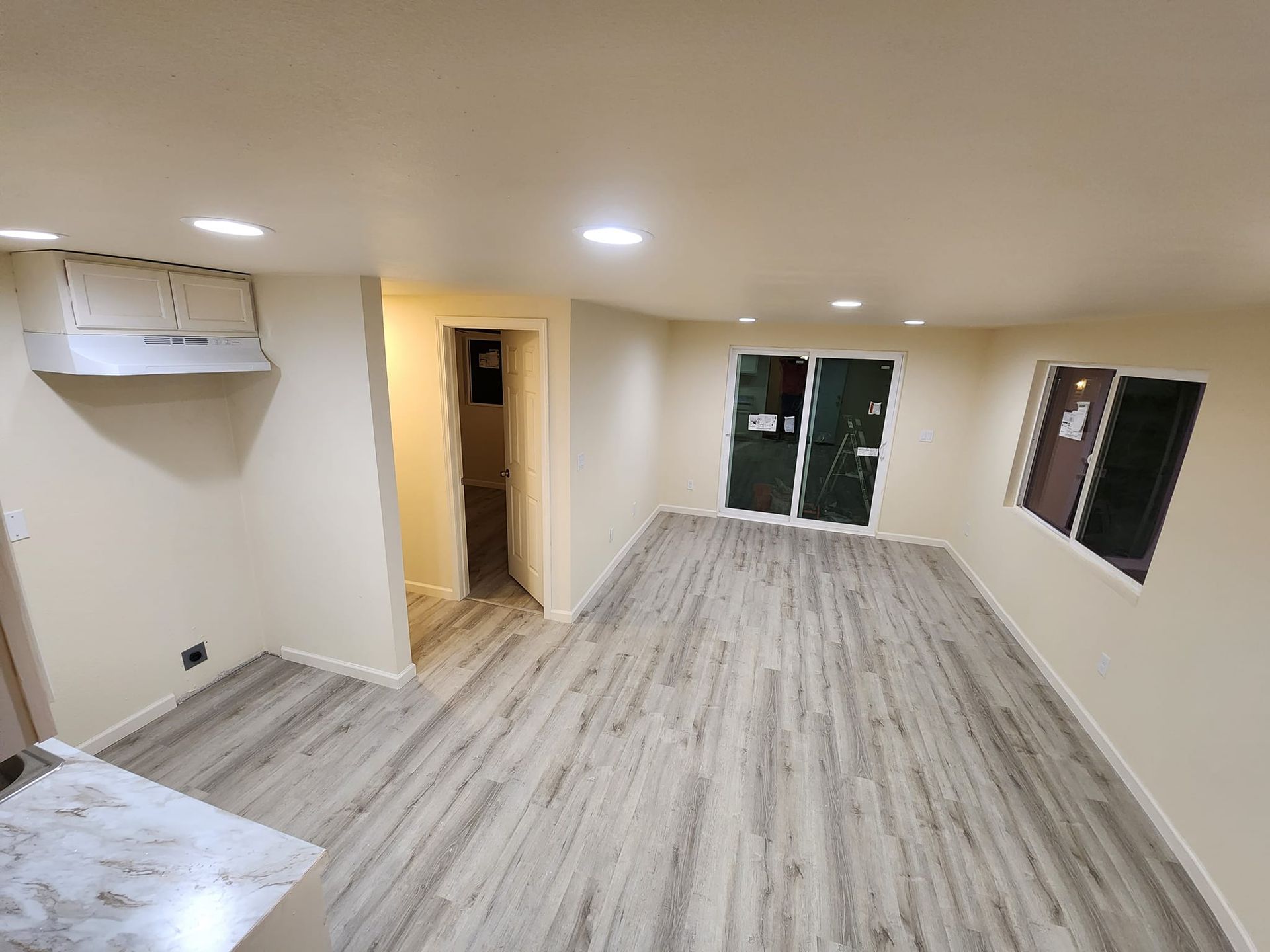 Empty room with beige walls, wood-look flooring, and recessed lighting. Features include a doorway