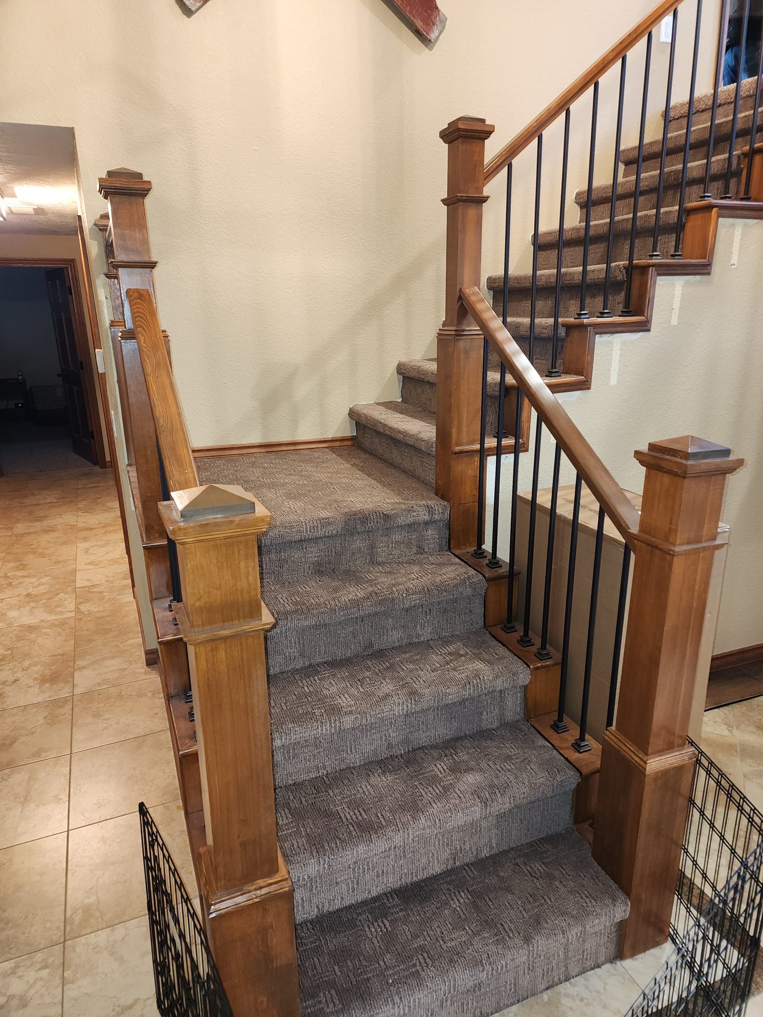 Staircase with brown wooden posts, black metal railings, and carpeted steps.