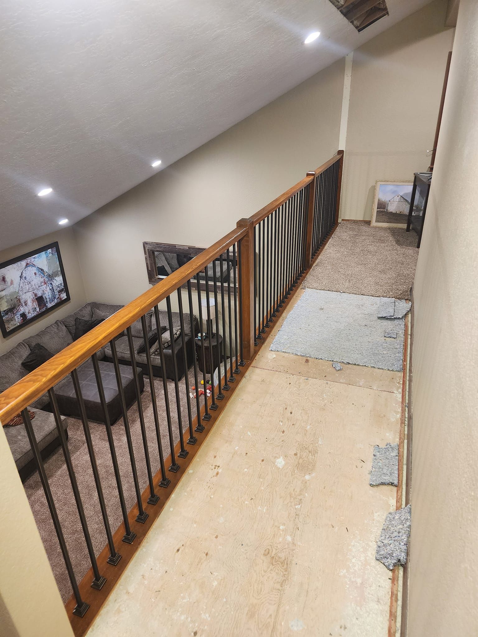 Staircase with brown railing and black vertical bars, carpeted stairs. Walls are tan.
