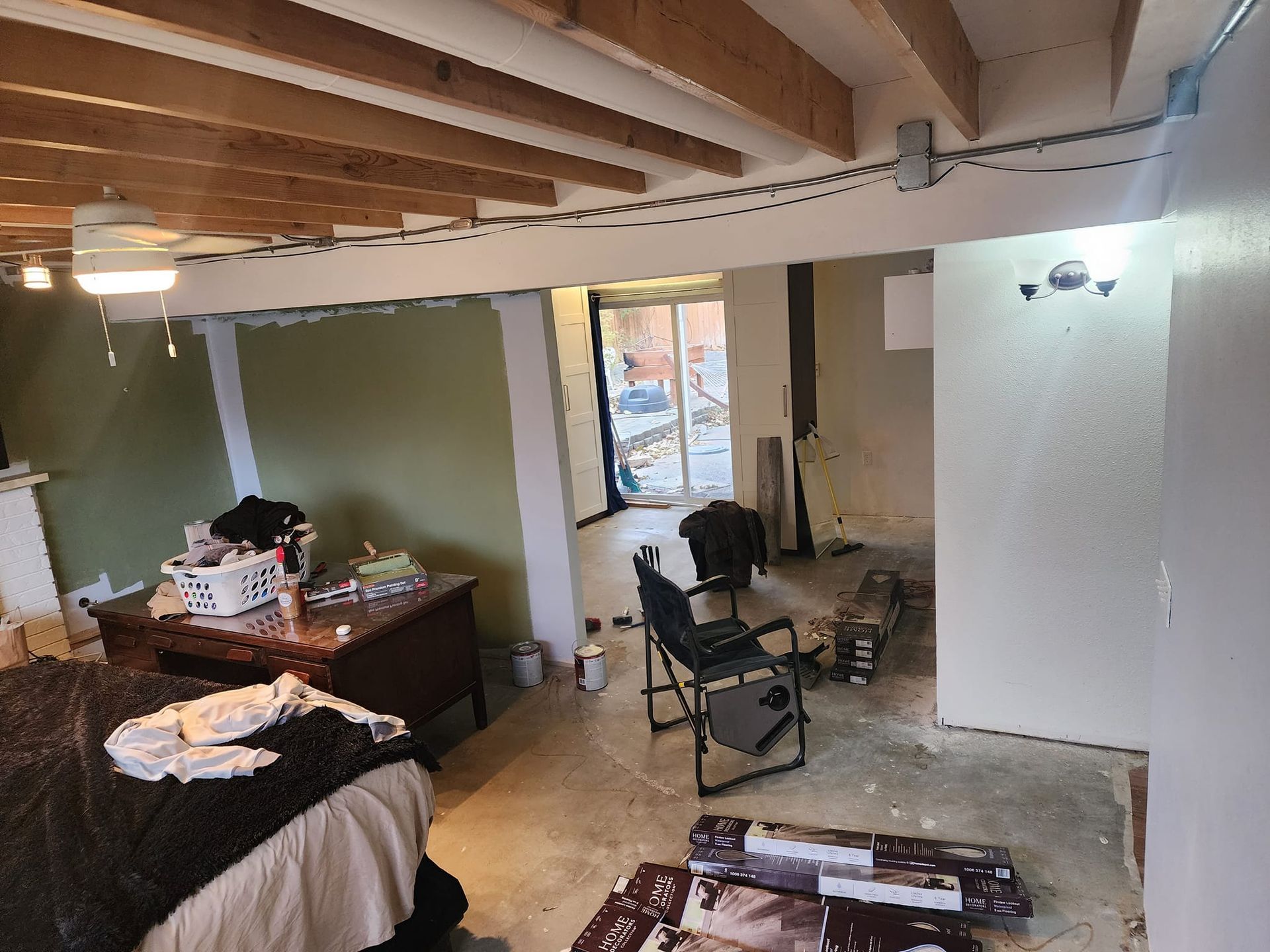 Room under renovation, exposed beams, unfinished walls. Items strewn about, chair, desk, debris.
