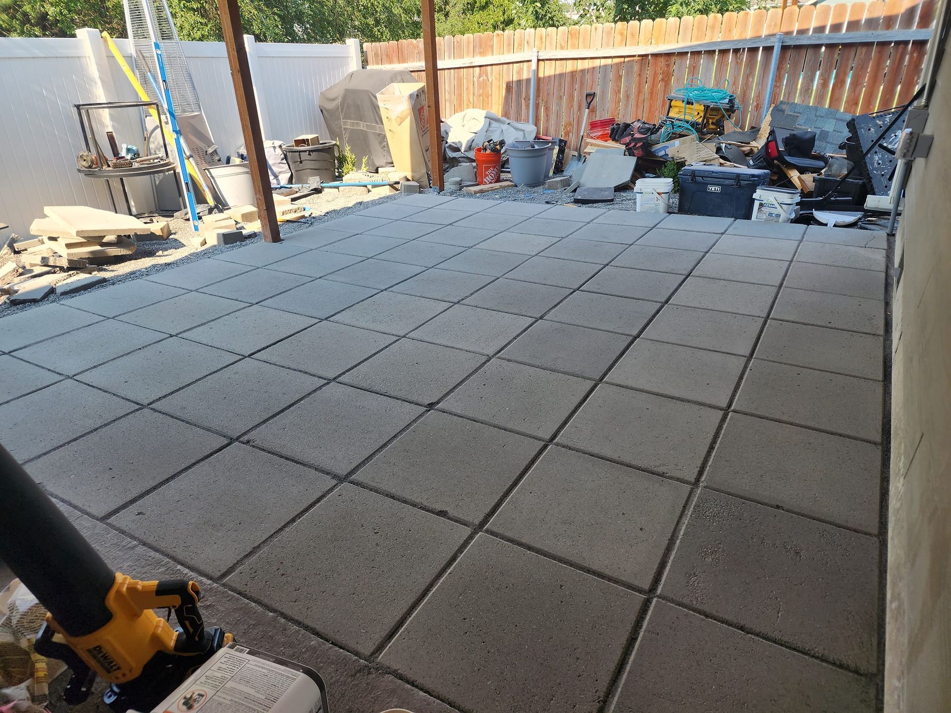 Newly laid gray concrete patio pavers in a backyard setting.