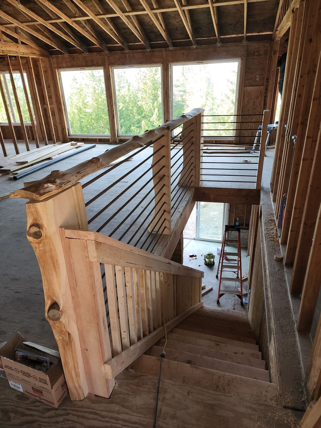 Interior view of a staircase under construction with wooden railings and metal balusters.