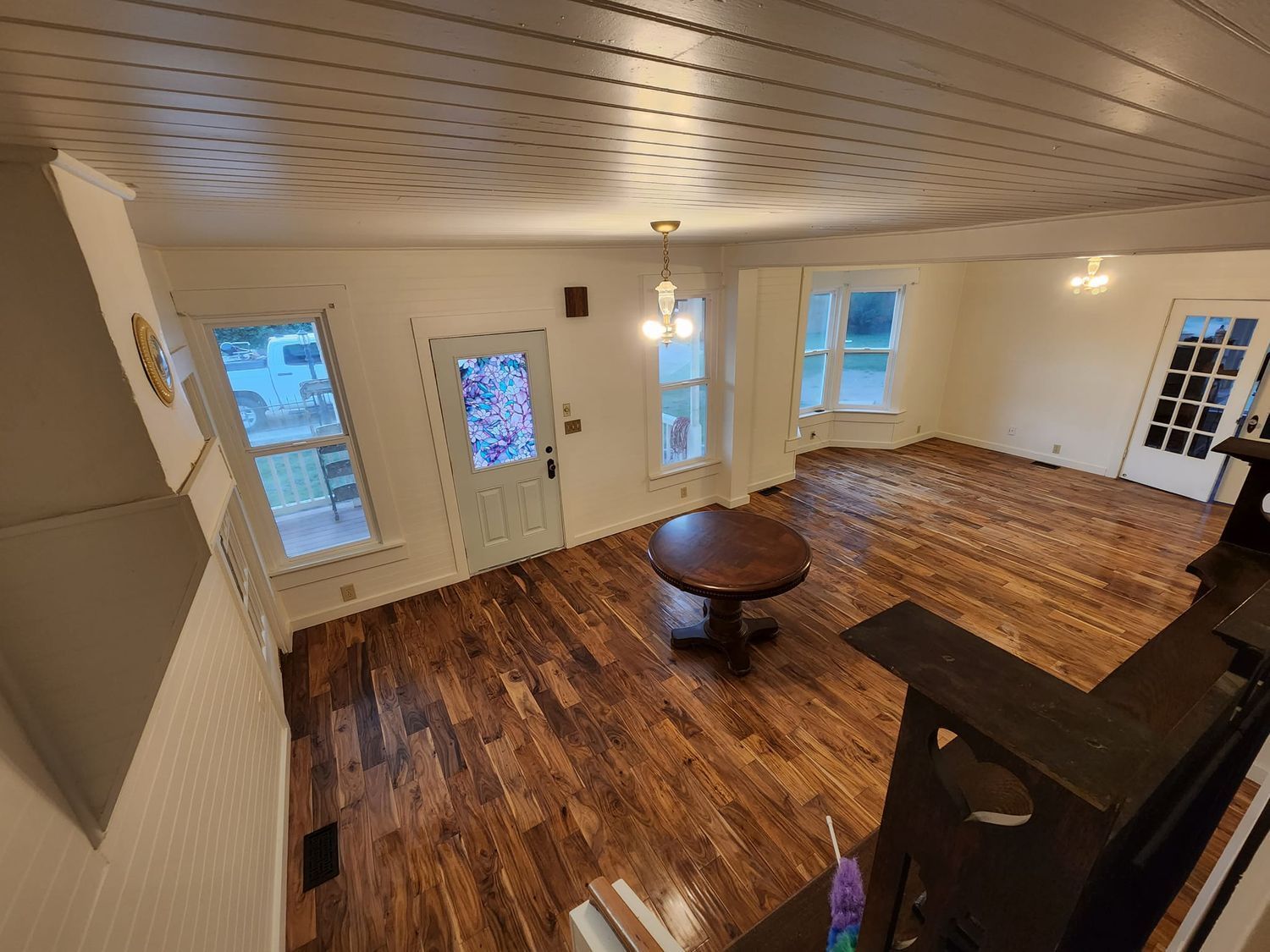 Interior view of a room with hardwood floors, white walls and a wood-paneled ceiling.
