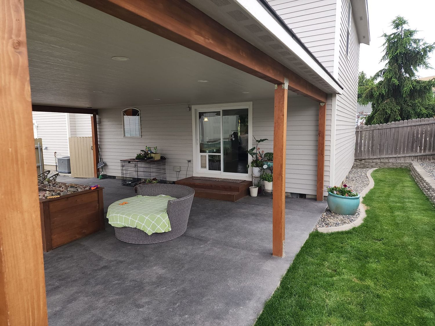 Covered patio with seating, garden bed, and sliding glass door.