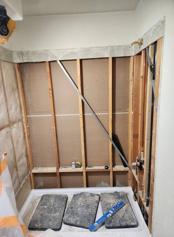 Bathroom under renovation; framing, plumbing, and a shower base are visible.
