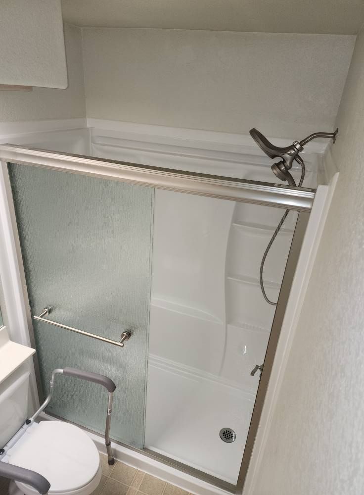 Bathroom with a sliding-door shower, grab bar, and a shower seat for accessibility.
